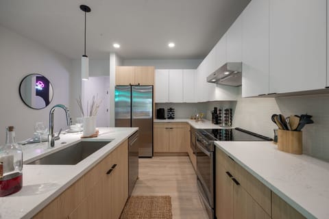 Fully equipped modern kitchen with basic cooking essentials, stainless steel appliances, island bar seating, Keurig coffee machine, and wet bar.