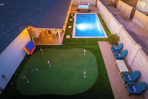 Aerial view of private backyard featuring pool, hot tub, minigolf green, covered patio, and lounge seating—perfect for family recreation and outdoor entertaining.