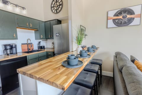 The modern kitchen boasts butcher block countertops, a deep gourmet sink, a Keurig and drip-style coffee station, and a central island perfect for shared meals.