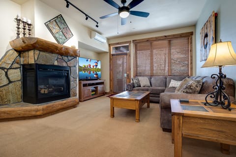 Unwind in your cozy living room with rustic stone fireplace, plush sectional, and mountain lodge charm that makes every evening feel special.