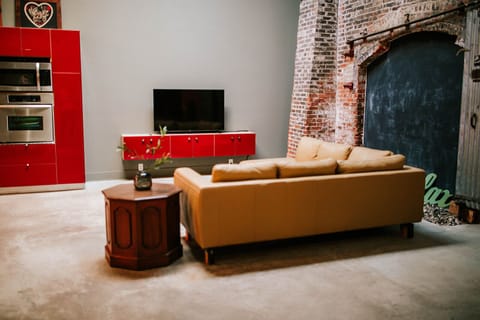 The open-concept living area boasts a striking floor-to-ceiling brick wall - a standout feature from the original warehouse construction!