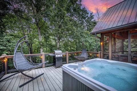 Enjoy the perfect retreat on the deck with a four-person hot tub overlooking serene nature views. This inviting space also features a gas grill and two cozy chaise swings, creating the ultimate setting for relaxation and outdoor fun.