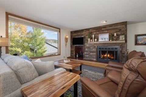 - Living room with fireplace and wood accent wall   - Comfortable seating with mountain views outside   - Inviting space for relaxing après ski evenings