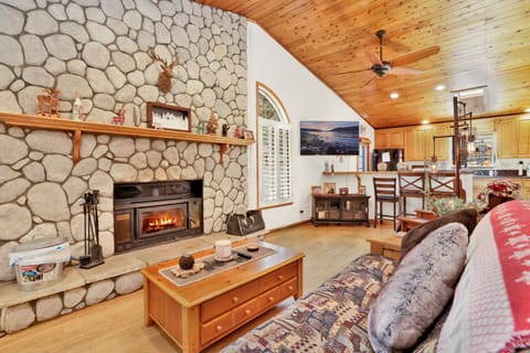 Cozy mountain living room with a stone fireplace, comfy seating, and smart TV—perfect for relaxing evenings, movie nights, and warm cabin vibes after outdoor adventures.