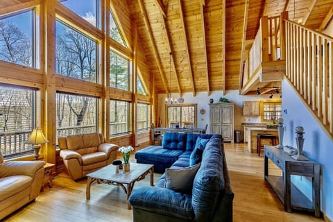 Open concept Living room with bamboo flooring, wooden A-framed ceiling, huge windows comfortable couches and arm chairs
