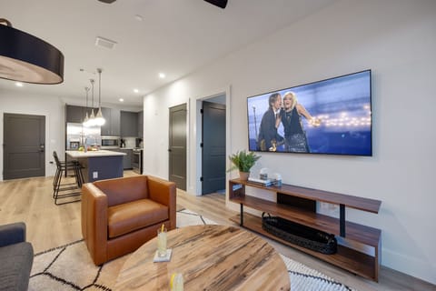 Open concept living area with smart TV, comfortable seating, designer decor, natural lighting, and access to private patio.