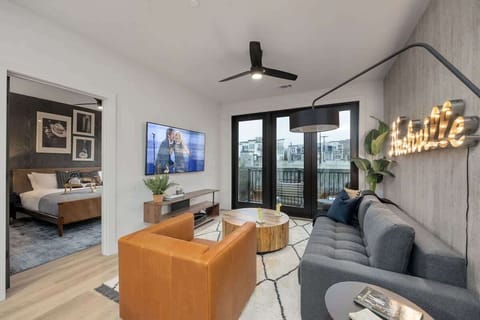 Open concept living area with smart TV, comfortable seating, designer decor, natural lighting, and access to private patio.