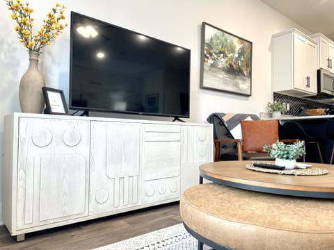 Living Room Bliss: Experience the Perfect Balance of Comfort and Entertainment in our Living Room, Featuring a Stunning 55-Inch TV as the Focal Point. Surrounding it, a Convenient Coffee Table, and a Plush Padded Ottoman Create the Ideal Setting for Relaxing, Socializing, and Enjoying Your Favorite Shows or Movies in Style.