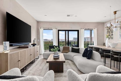 The stylish living room has a unique curved sofa, large windows, and a sophisticated ambiance, ideal for modern living.
