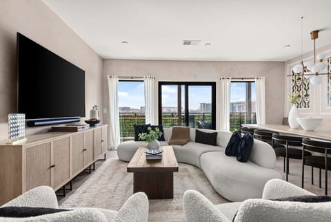 The stylish living room has a unique curved sofa, large windows, and a sophisticated ambiance, ideal for modern living.