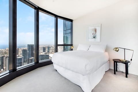 The spacious master bedroom features a queen-size bed and floor-to-ceiling windows offering stunning views of the city.
