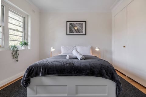 The master bedroom is flooded with natural light from the large windows, with beautiful white wooden shutters for privacy
