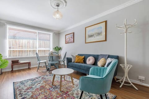 Experience the charm of cottage-inspired design with a velvet lounge and chair, a soft rug on timber floors, and entertainment on the TV—plus space to hang your coats in winter.