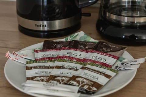 A close-up of complimentary coffee sachets and a kettle on a countertop.

