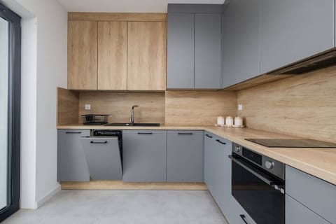 A sleek kitchen with grey cabinets, wooden countertops, and built-in appliances, blending style and functionality.