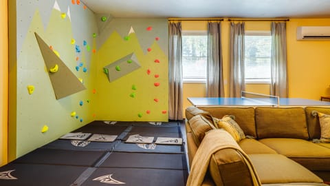 The Retreat: Professionally-built bouldering wall with safety mats, for adults & kids.  Join the action to play foosball, ping pong, or Nintendo Switch.  Or perhaps just take in an action movie on the 75" screen and Article couch.  (for more action: 120" projection in the Theatre room-see other pic)