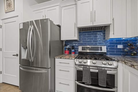 "Modern kitchen at Wimberley Retreat — stainless steel appliances, vibrant blue backsplash, and sleek design for a stylish Texas stay.