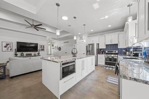 Fully equipped kitchen with stainless steel appliances, granite countertops, and white cabinets.