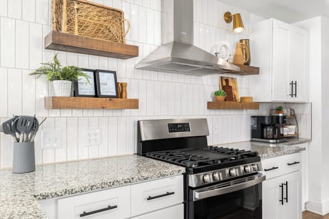 Elevate your cooking experience in this elegant kitchen featuring white cabinets and a bold black stove