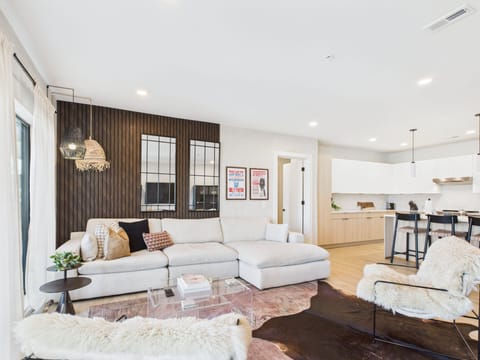 Cozy modern living room featuring a Smart TV, Patio access with city views and designer decor with plush furnishings.