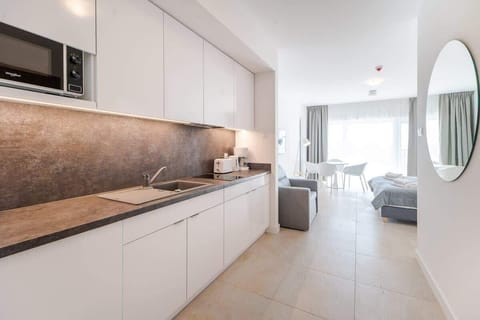 A modern kitchen with white cabinets, stone countertops, and built-in appliances, designed for both style and efficiency.

