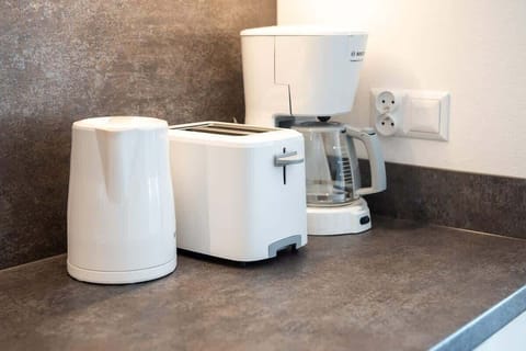 A coffee and tea station on the kitchen countertop, featuring a kettle, a toaster, and a coffee machine, adding convenience to the space.