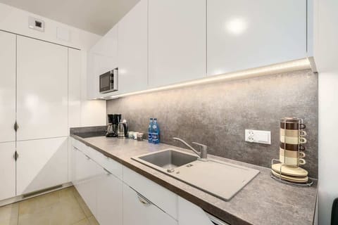 A bright and functional kitchen with white cabinets, modern appliances, and a gray countertop, designed for convenience.
