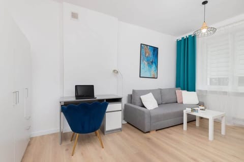 A view of the living and dining area, showcasing a grey sofa, a blue armchair, and wooden flooring.
