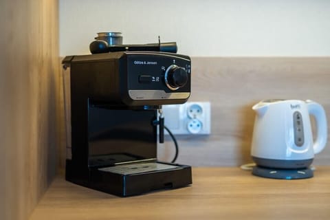 A close-up of a coffee station with a coffee maker and kettle placed on a wooden countertop, providing convenience and style.
