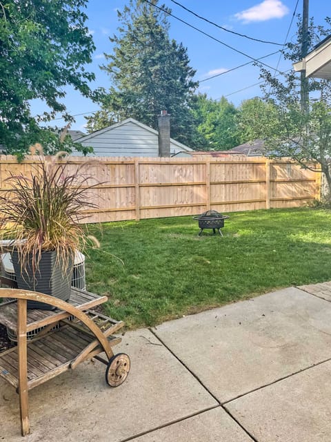 Outside living space with firepit, grill, and a partially fenced-in yard.