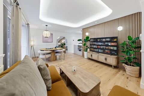 Open living space with feature wall, media unit, dining area and light wood flooring throughout