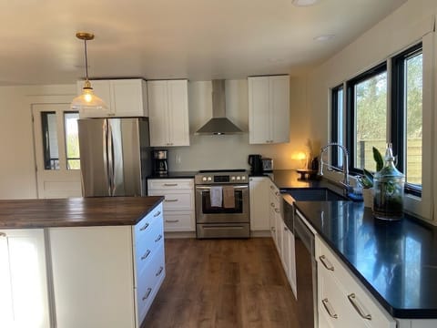 Chef’s kitchen with modern appliances, butcher block island, quartz counters, and everything you need to cook at home - from blender to casserole dishes.