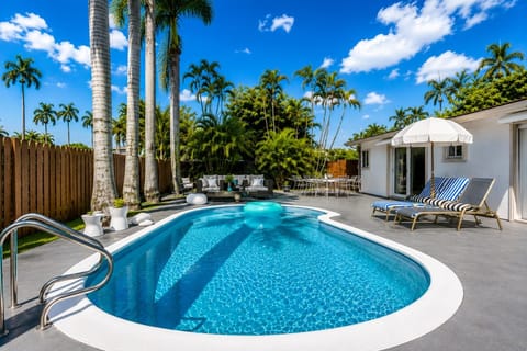Spacious private backyard with a pool, concrete deck, sun loungers, umbrella and outdoor dining table.Fully fenced for privacy and quiet, a great setup for families and groups.