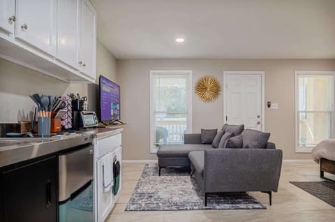 Bright and inviting area featuring a comfy sectional, modern decor, and plenty of natural light—perfect for lounging or catching up on your favorite shows.