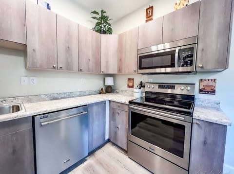 Kitchen with 5-burner chrome stove and full-size chrome microwave 