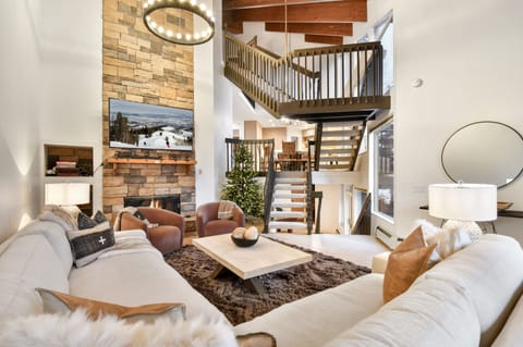 Cozy mountain living room with soaring ceilings, stone fireplace, and open loft design—perfect for après-ski evenings.