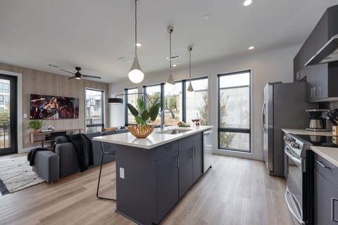 Fully equipped kitchen with stainless steel appliances, basic cooking essentials, toaster, coffee machine, and kitchen island seating.