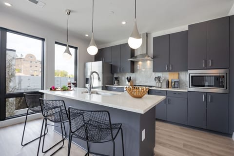 Fully equipped kitchen with stainless steel appliances, basic cooking essentials, toaster, coffee machine, and kitchen island seating.