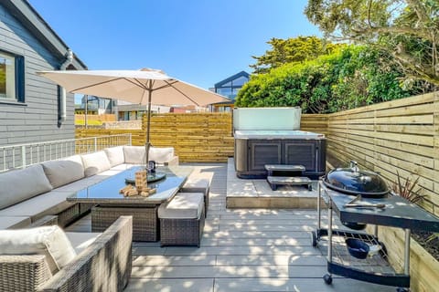 The deck area at the rear with rattan furniture, BBQ and private hot tub