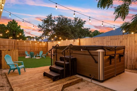 A cozy backyard oasis with a glowing hot tub, string lights, & relaxed seating.