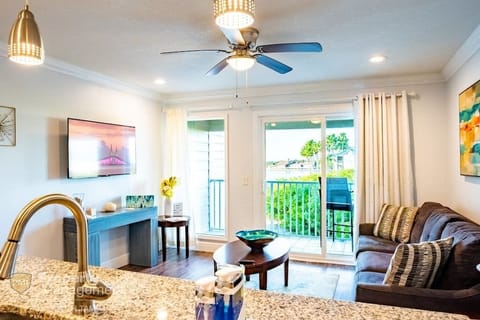 View of living room area with generous island, large screen smart TV, and comfy sofa with pullout provides sleeping arrangements for a queen-sized bed