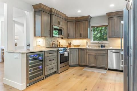 Fully stocked kitchen with beverage fridge and door to outdoor patio dining