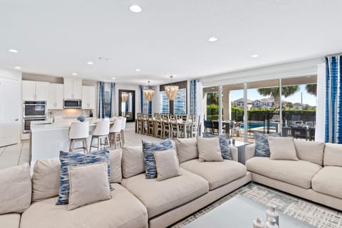 - Bright open space with sliding doors to the pool  
- Comfortable sofas and stylish blue accent décor  
- Dining and kitchen areas designed for large groups