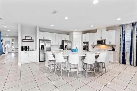 - Modern white kitchen with double stainless fridges  
- Oversized island with barstools for casual dining  
- Fully stocked space ready for family cooking fun