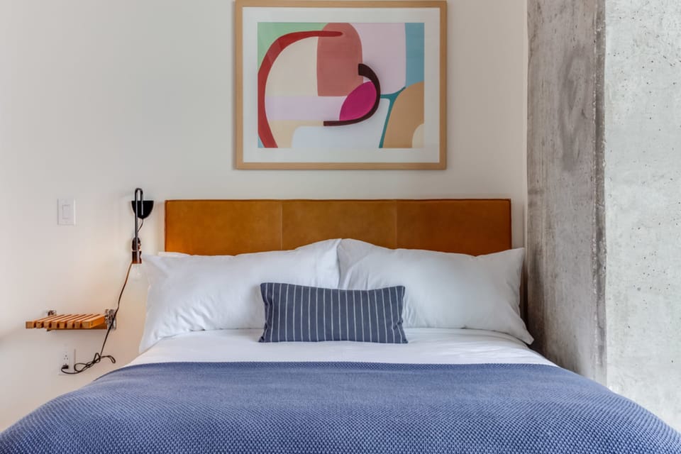 Rest easy in a beautifully curated queen bedroom featuring modern art, plush linens, and a warm, inviting design.