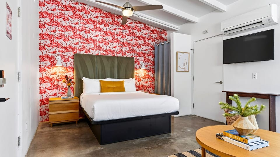 The Queen Studio features a plush queen bed, TV, ceiling fan, and vibrant Palm Springs style.