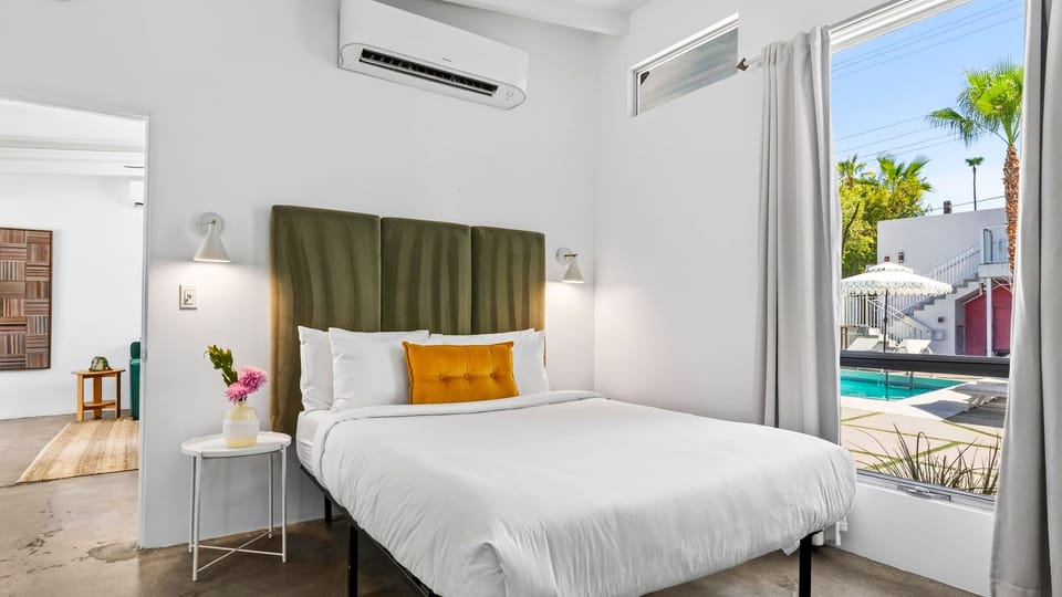 A king bed anchors this bright retreat, with oversized windows framing views of the pool courtyard just outside.