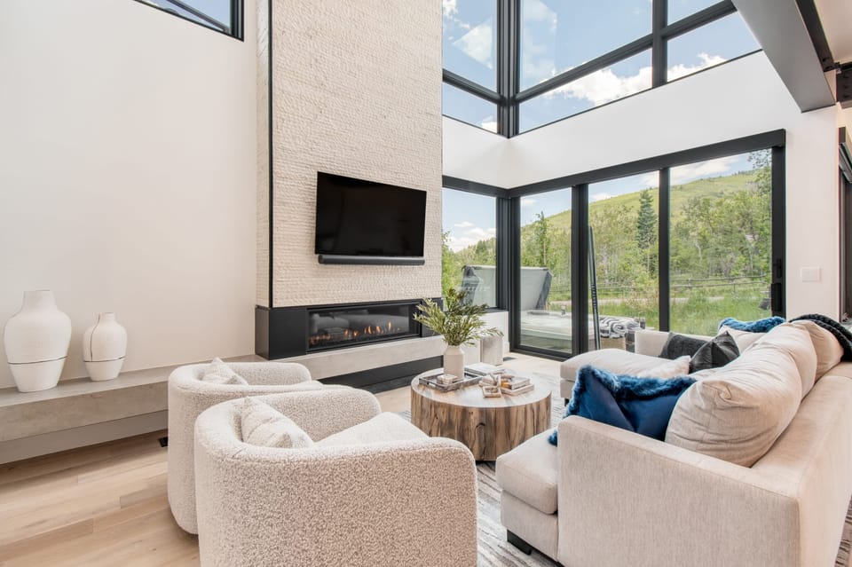 Modern living room with tall ceilings, large windows, and an electric firepit.
