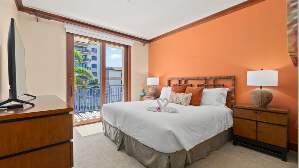 Primary bedroom features a king bed, balcony, ensuite bathroom, and TV.