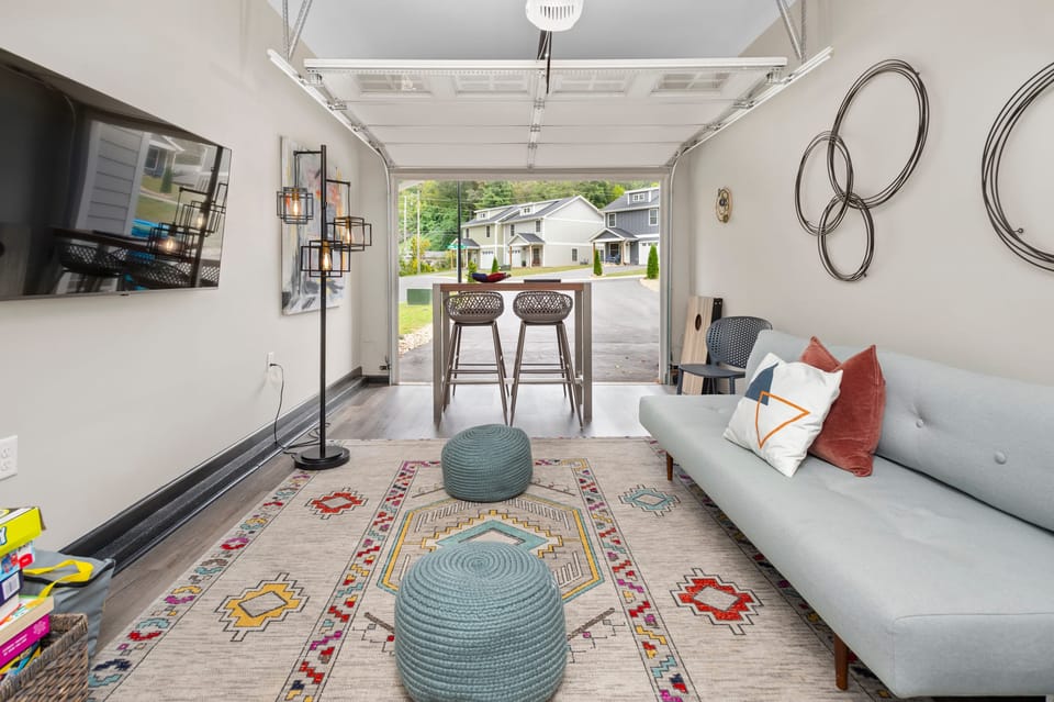 Converted garage lounge features a sleep sofa, TV, and table perfect for games.